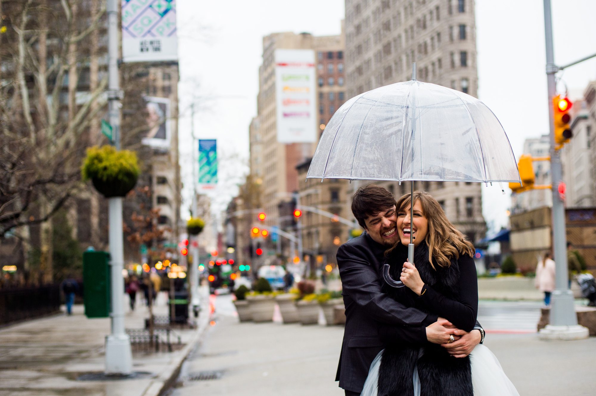 A couple is snuggling under an umbrella after their rainy day wedding in NYC