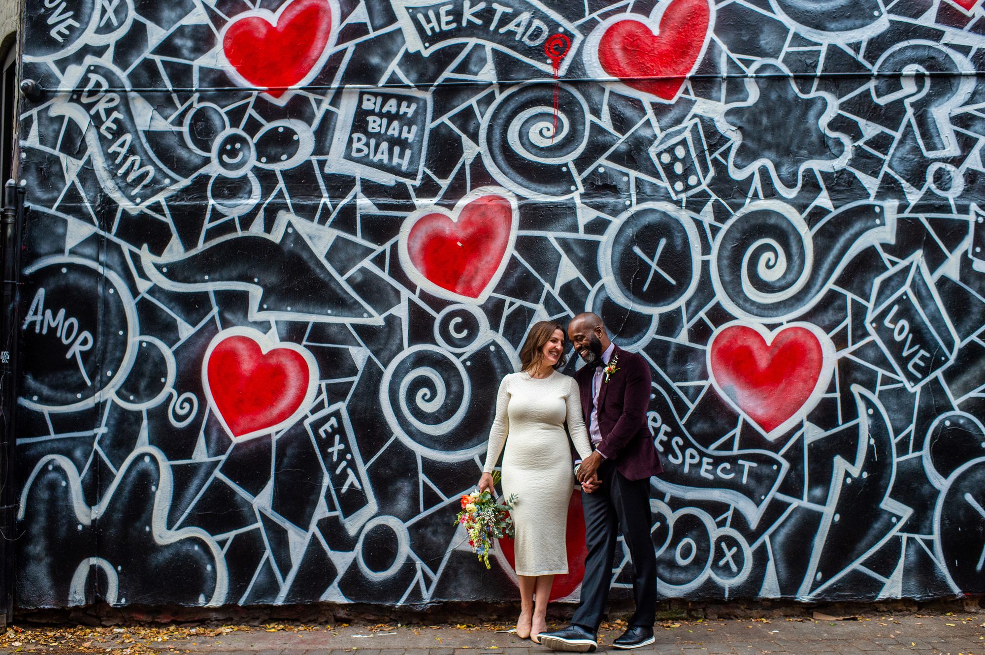 A couple in front of the graffiti wall at First Street Art Park for their NYC elopement. 