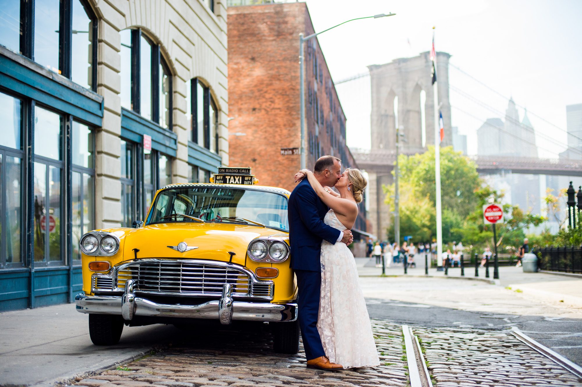 A couple kiss while leaning against a vintage taxi cab after their Brooklyn Elopement. 