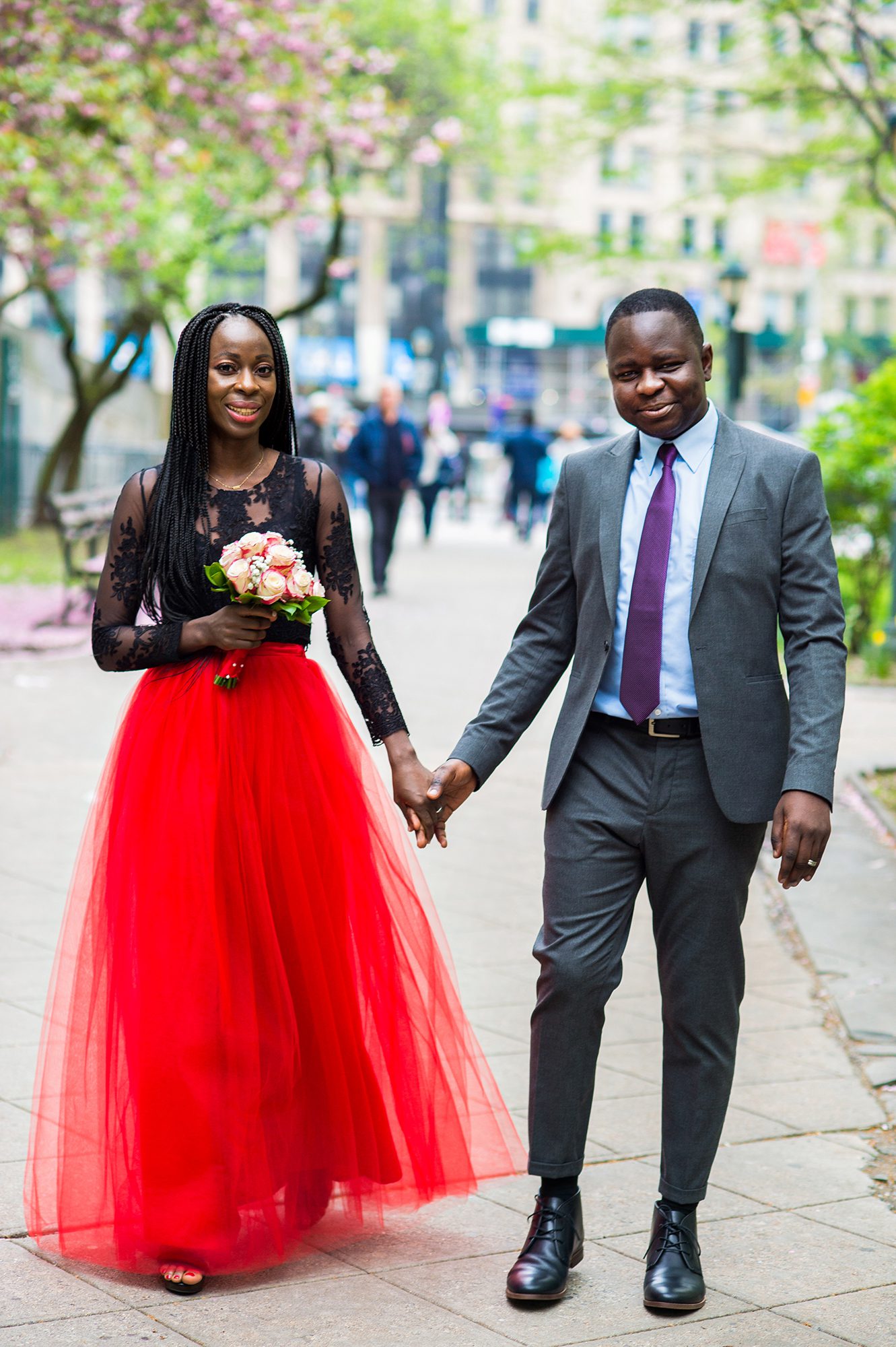 Couple after their City Hall wedding walking. Bride is in a bright red skirt.