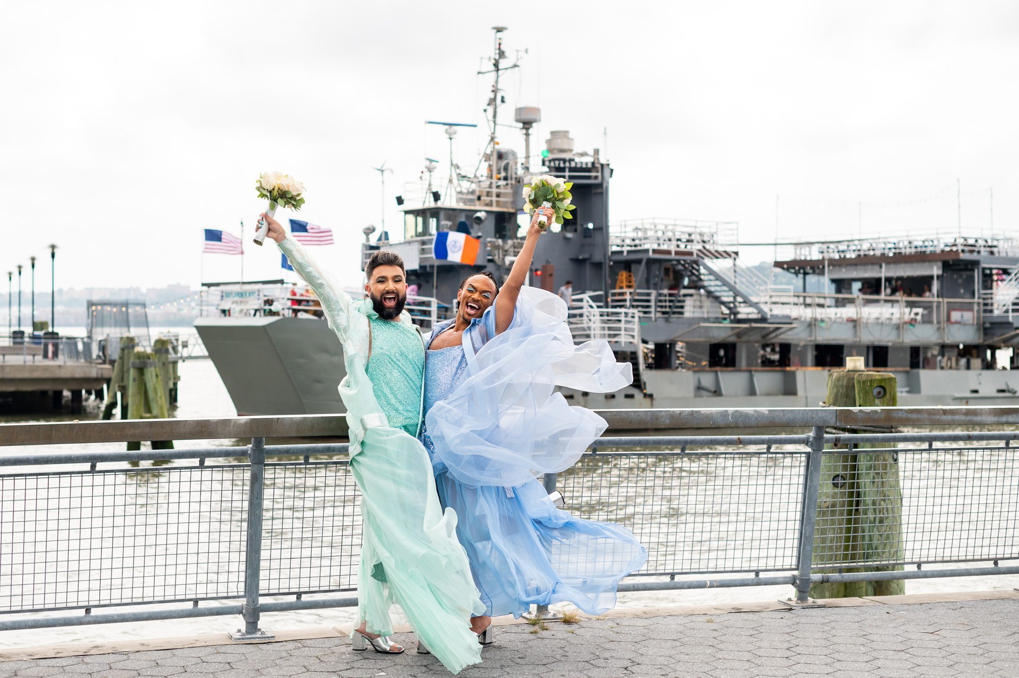 Two grooms cheering before their wedding standing in front of Baylander Steel Beach. 
