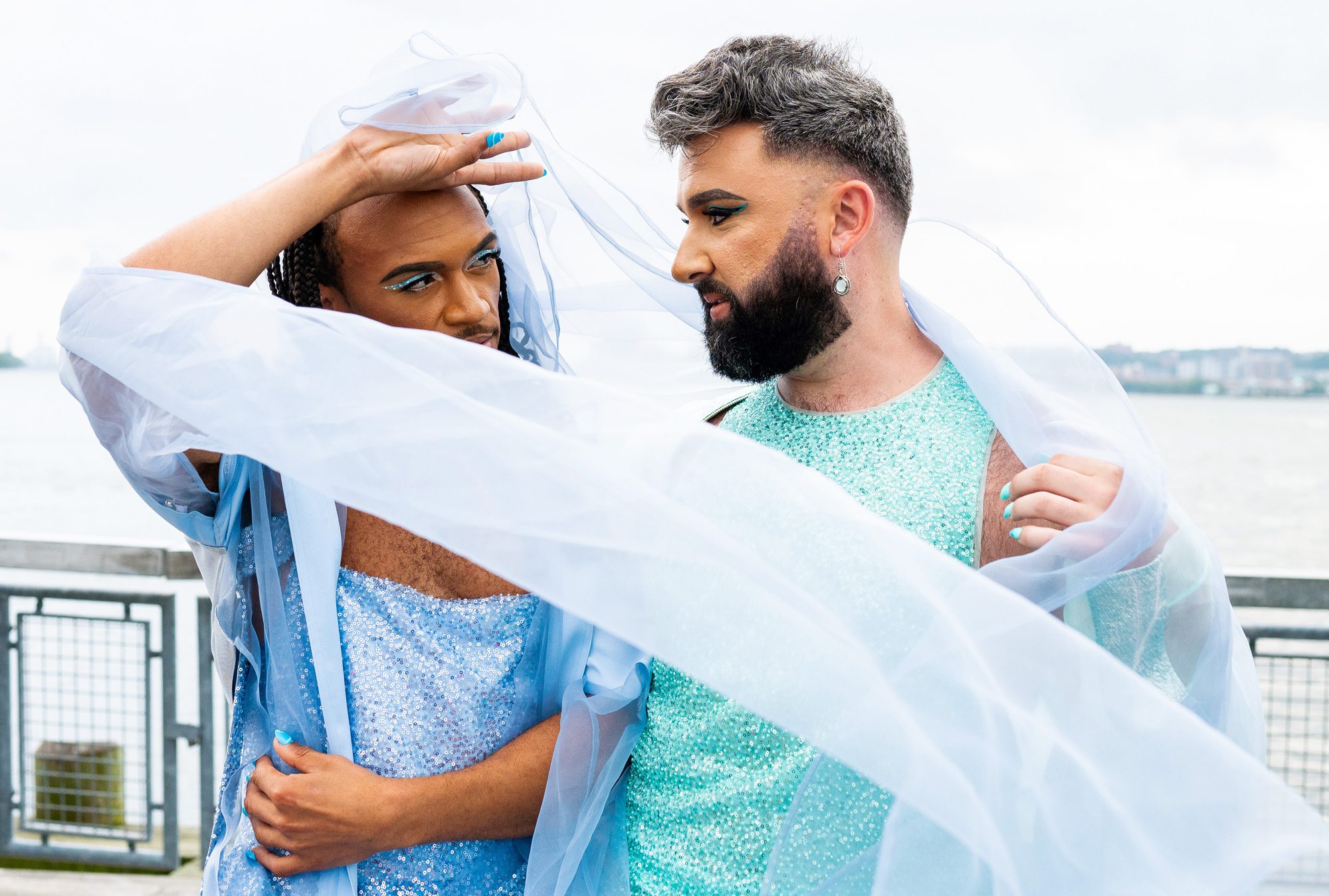 A couple with a veil swirling around them in sparkly outfits. 