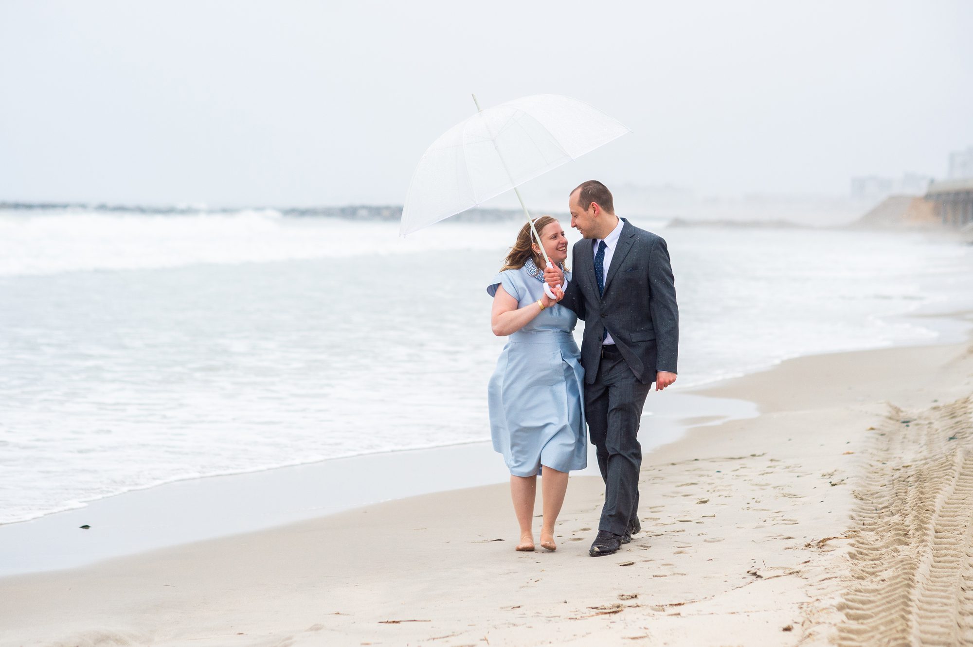 Couple walking on Rockaway Beach after their NYC Elopement on a rainy day. 