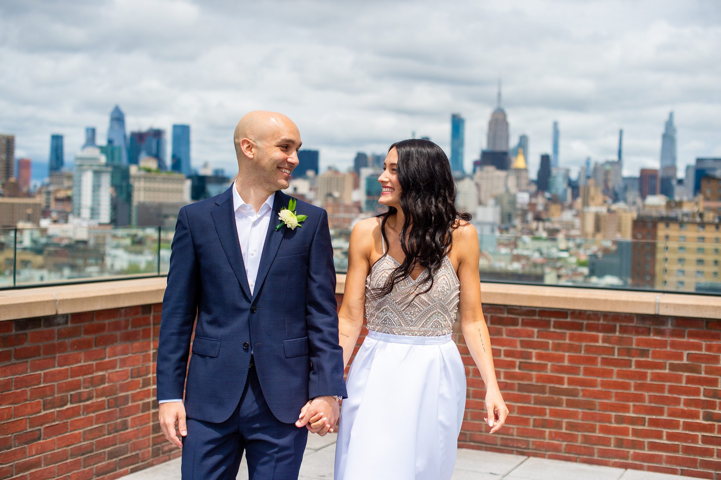 Couple walking on a hotel rooftop with the NYC Skyline behind them