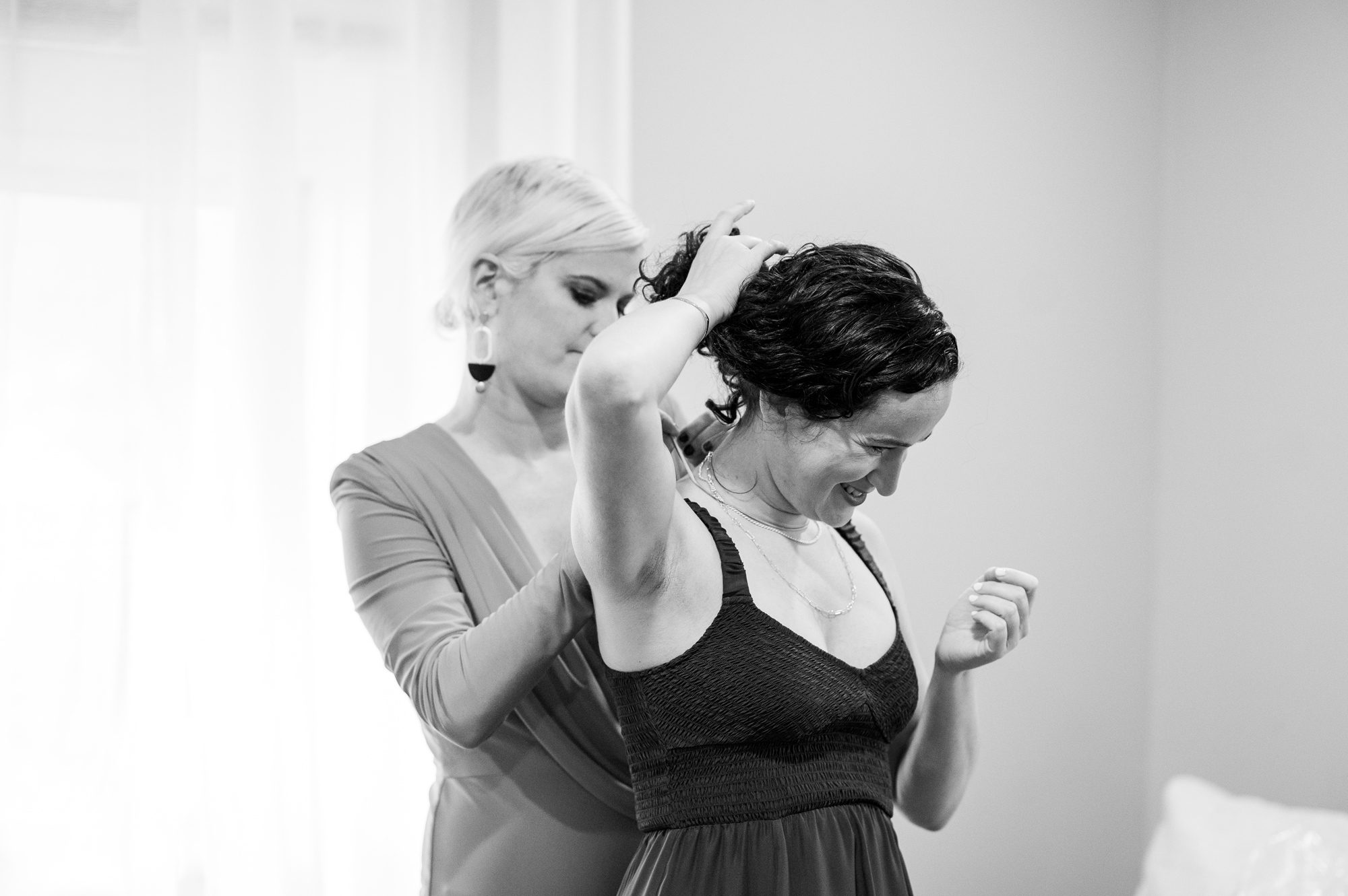 Sister helping bride get ready at wedding on Roosevelt Island