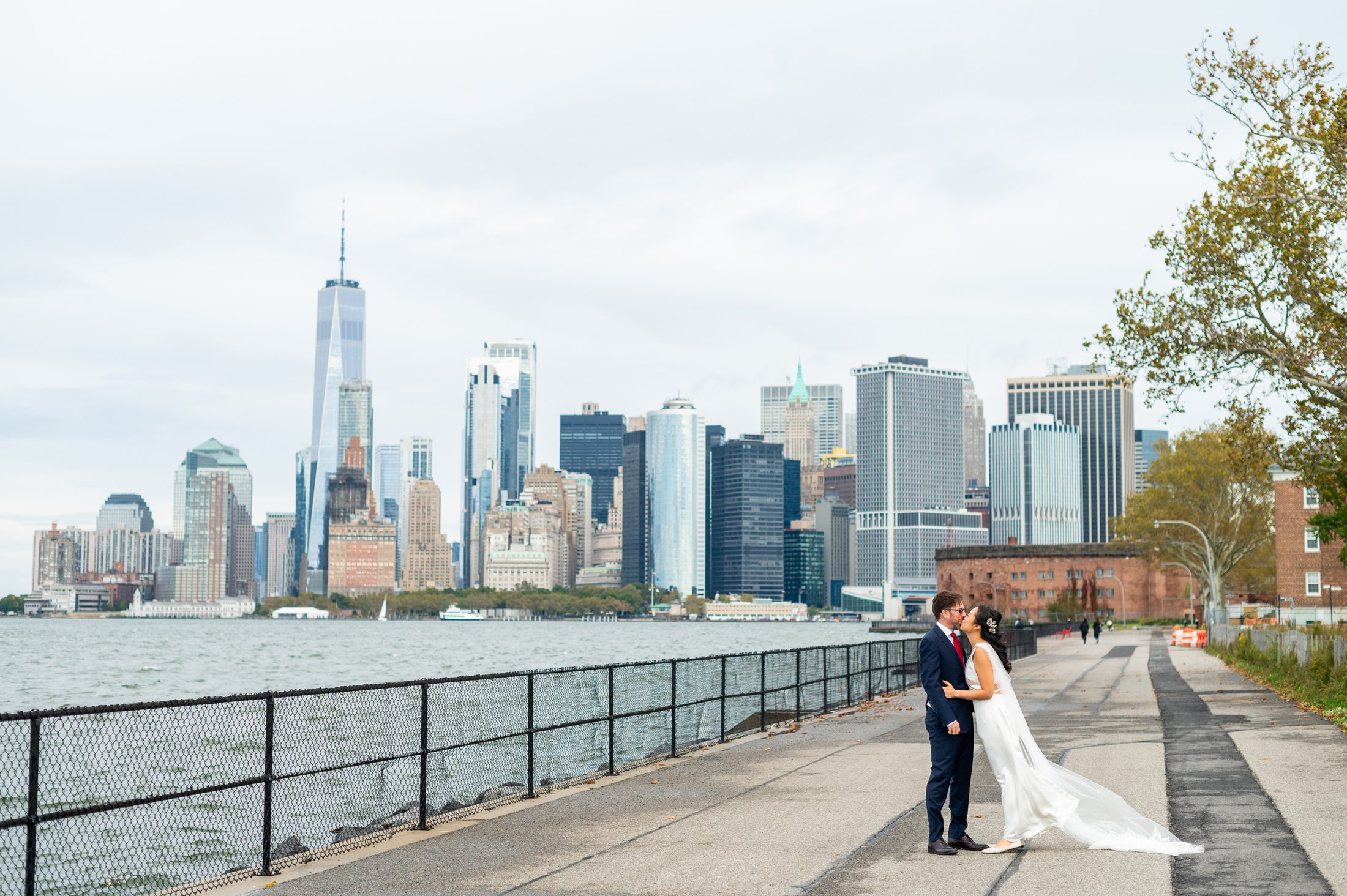 Bride and Groom kissing with NYC Skyline in the background on Governors Island 