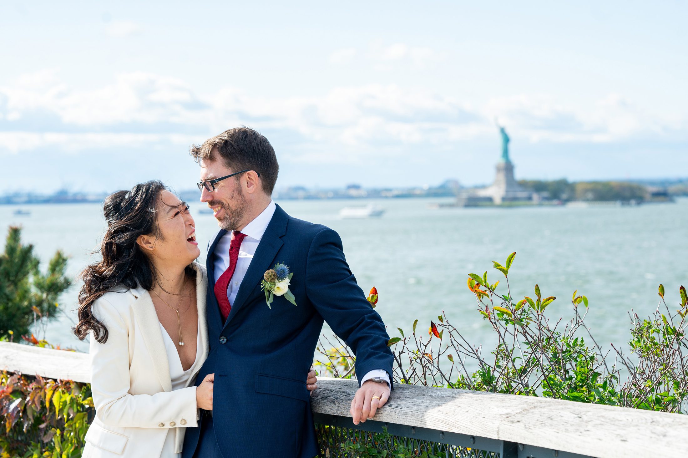 Bride and Groom on Governors Island in NYC with Statue of Liberty in the background. 