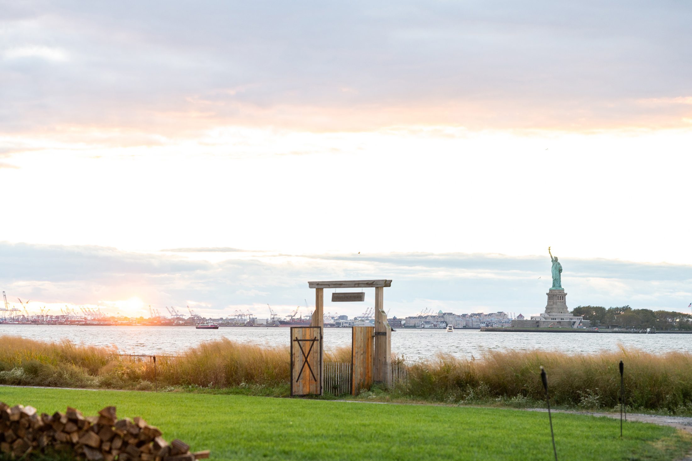 Sunset view of gate at Governors Island Collective Retreats with statue of liberty. 