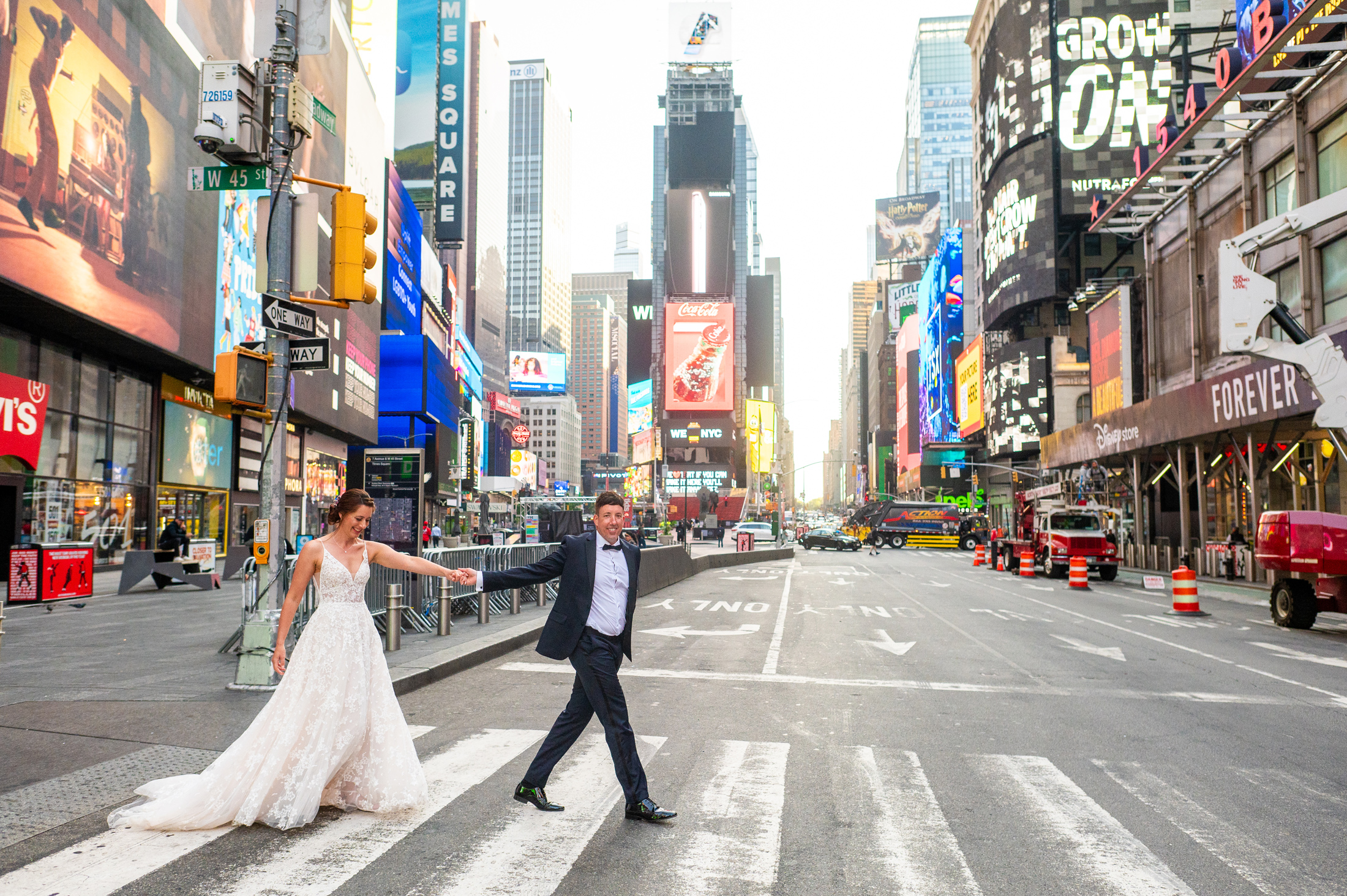 Bride and groom walking across the street in Times Square. 