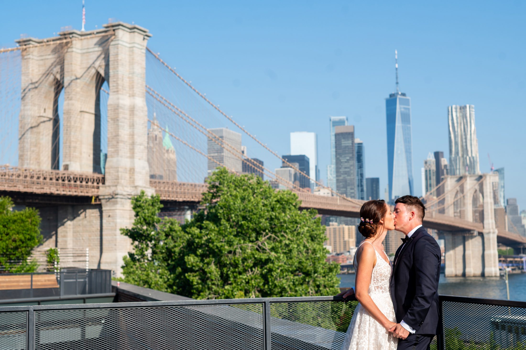Bride and Groom kissing with Brooklyn Bridge in the background. 