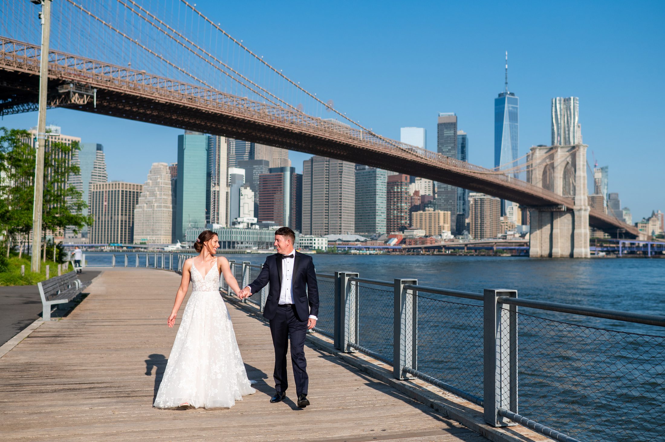 Couple walking with Brooklyn Bridge in the background. 