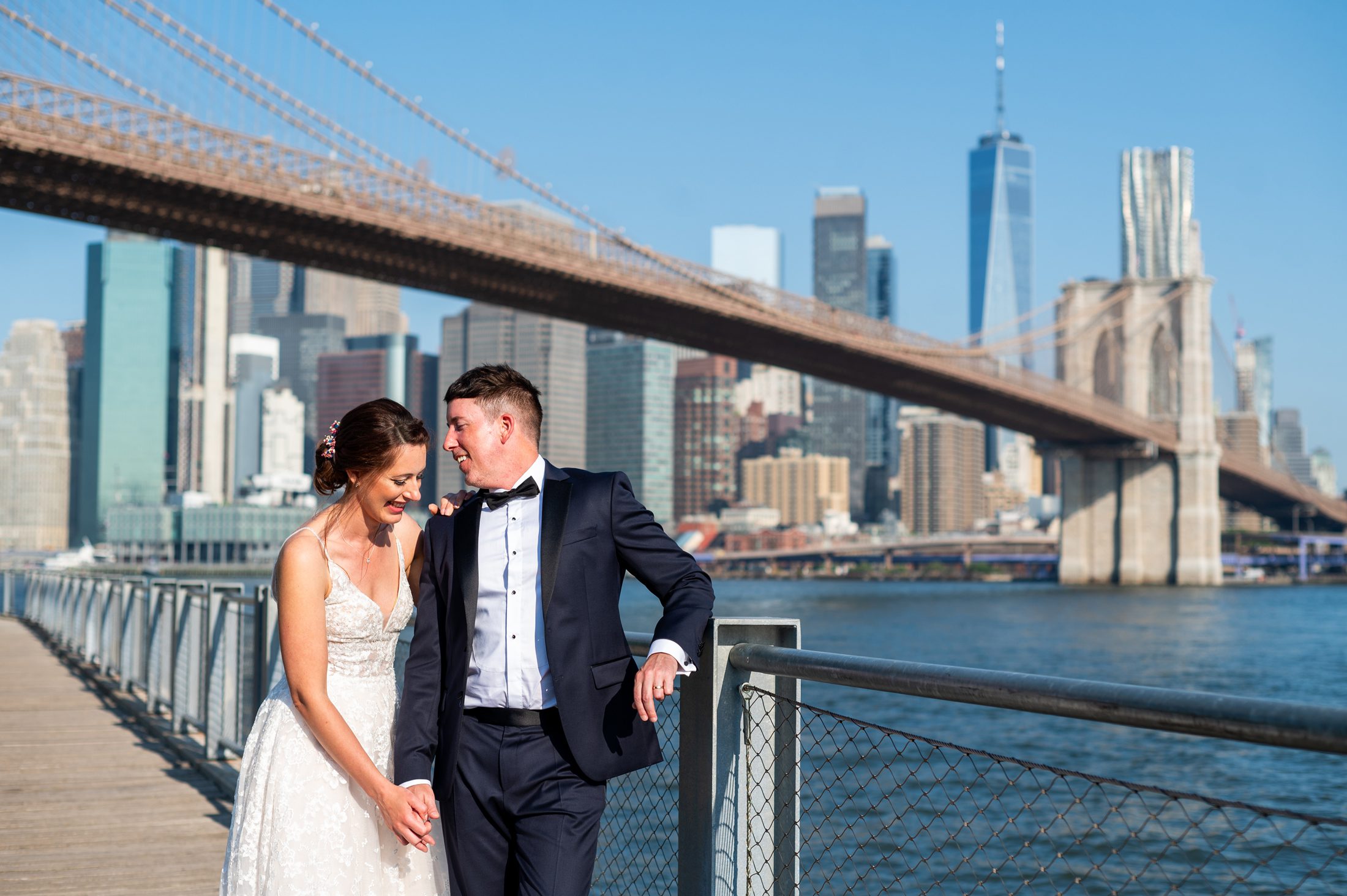 Bride and Groom talking with Brooklyn Bridge in the background. 