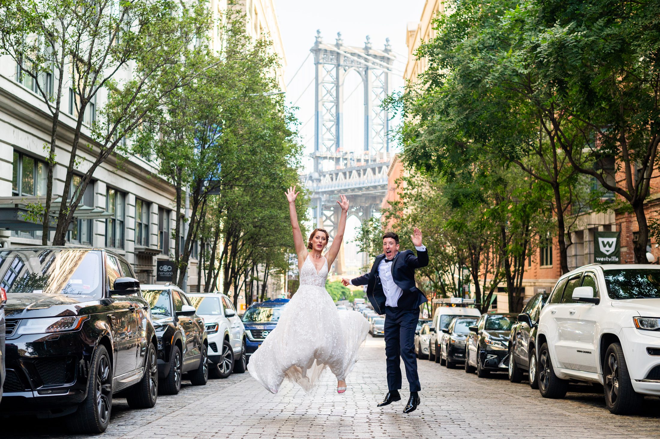 Bride and groom jumping on the street in Brooklyn with Manhattan Bridge. 