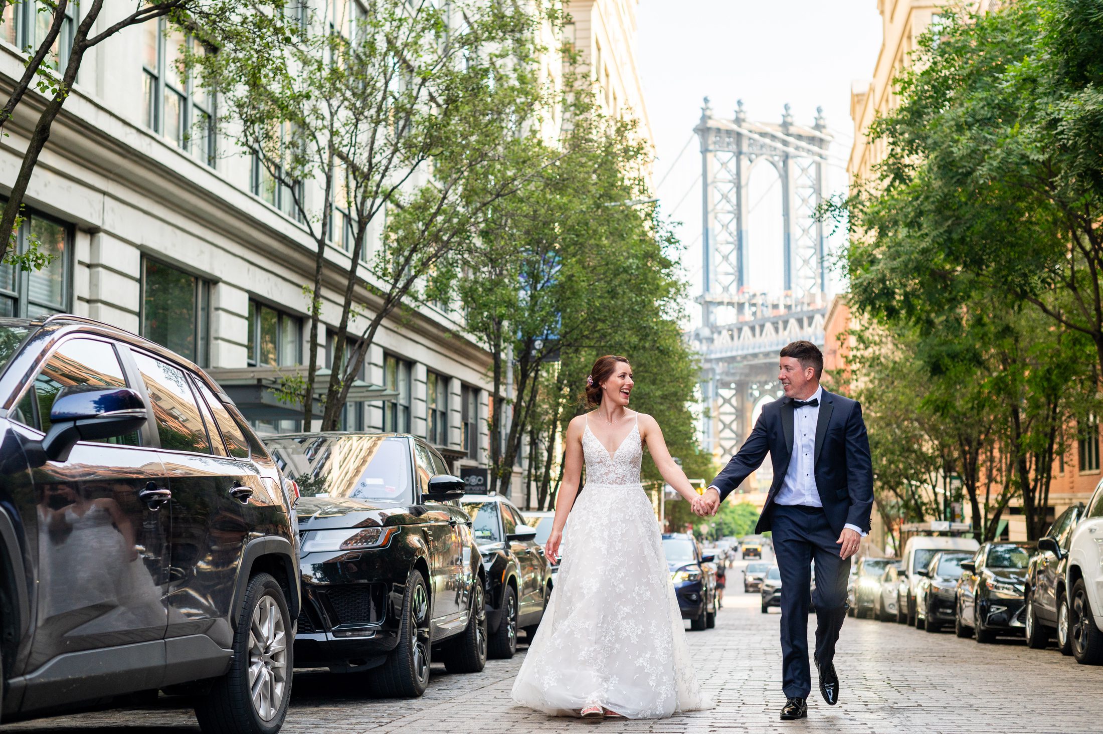 Bride and groom walking on the street with Manhattan Bridge behind them. 