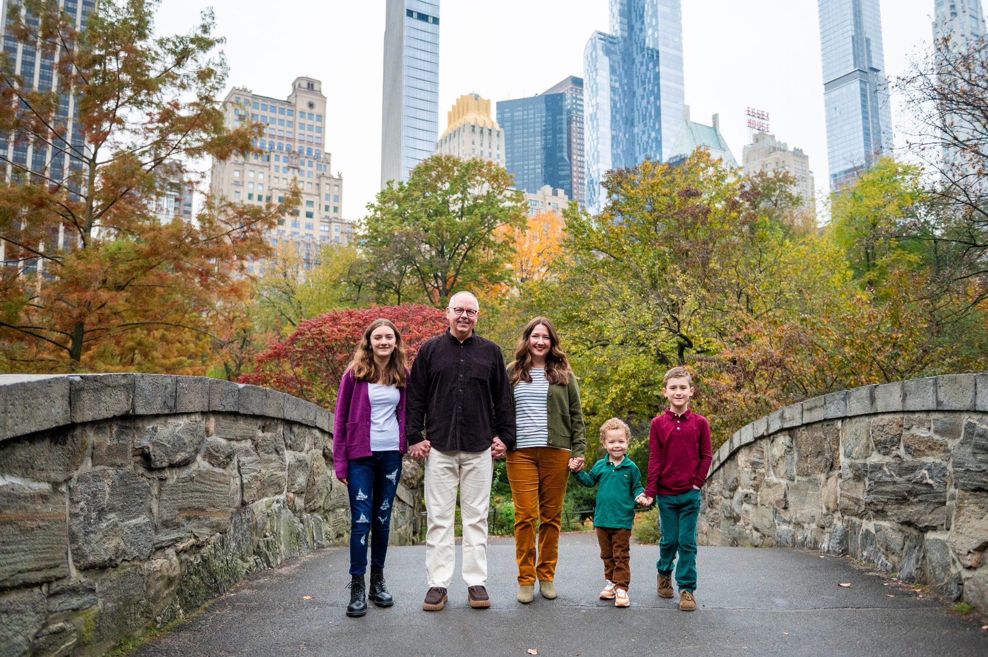 Family walking over Gapstow Bridge in Central Park in the fall 