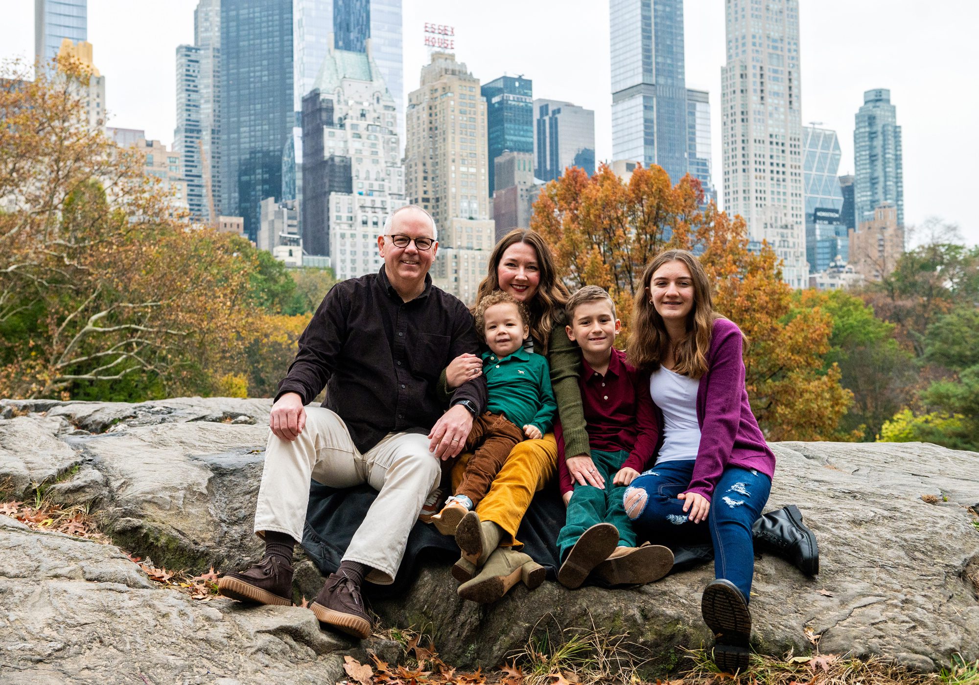 Family getting their photo taken in Central Park with the NYC skyline behind them. 