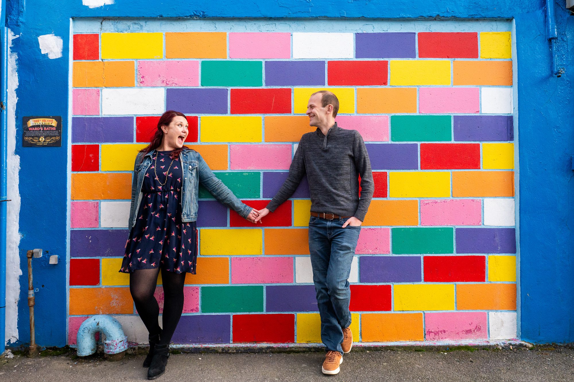 Couple in front of rainbow colored block wall in Coney Island