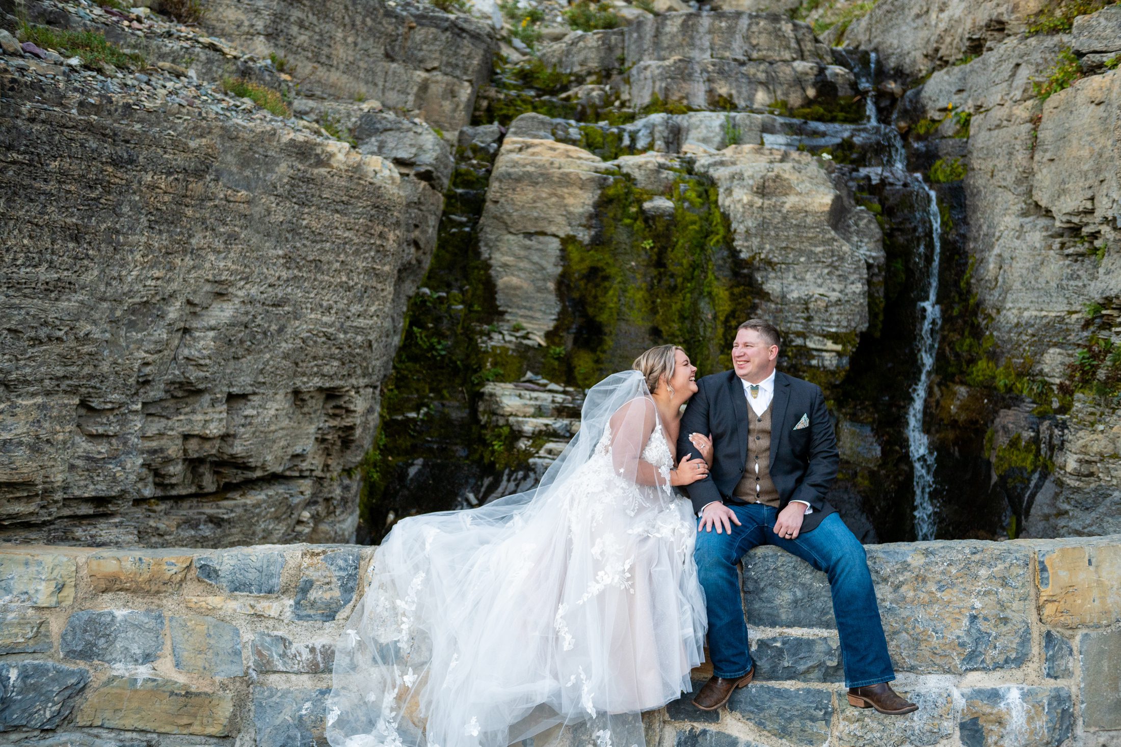 Couple by a waterfall in Glacier National Park taking wedding photos