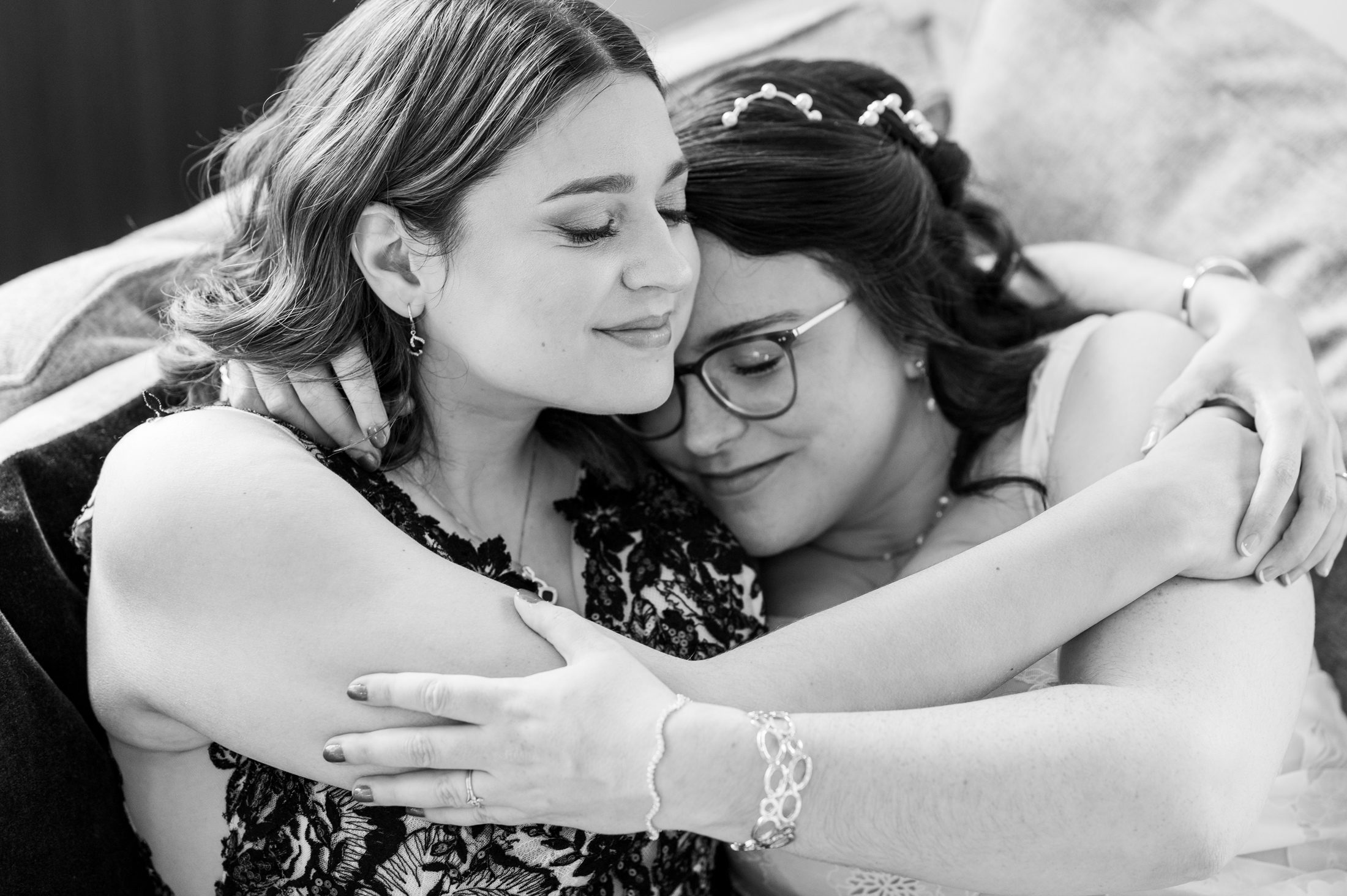 Black and white photo of two brides snuggling on a couch