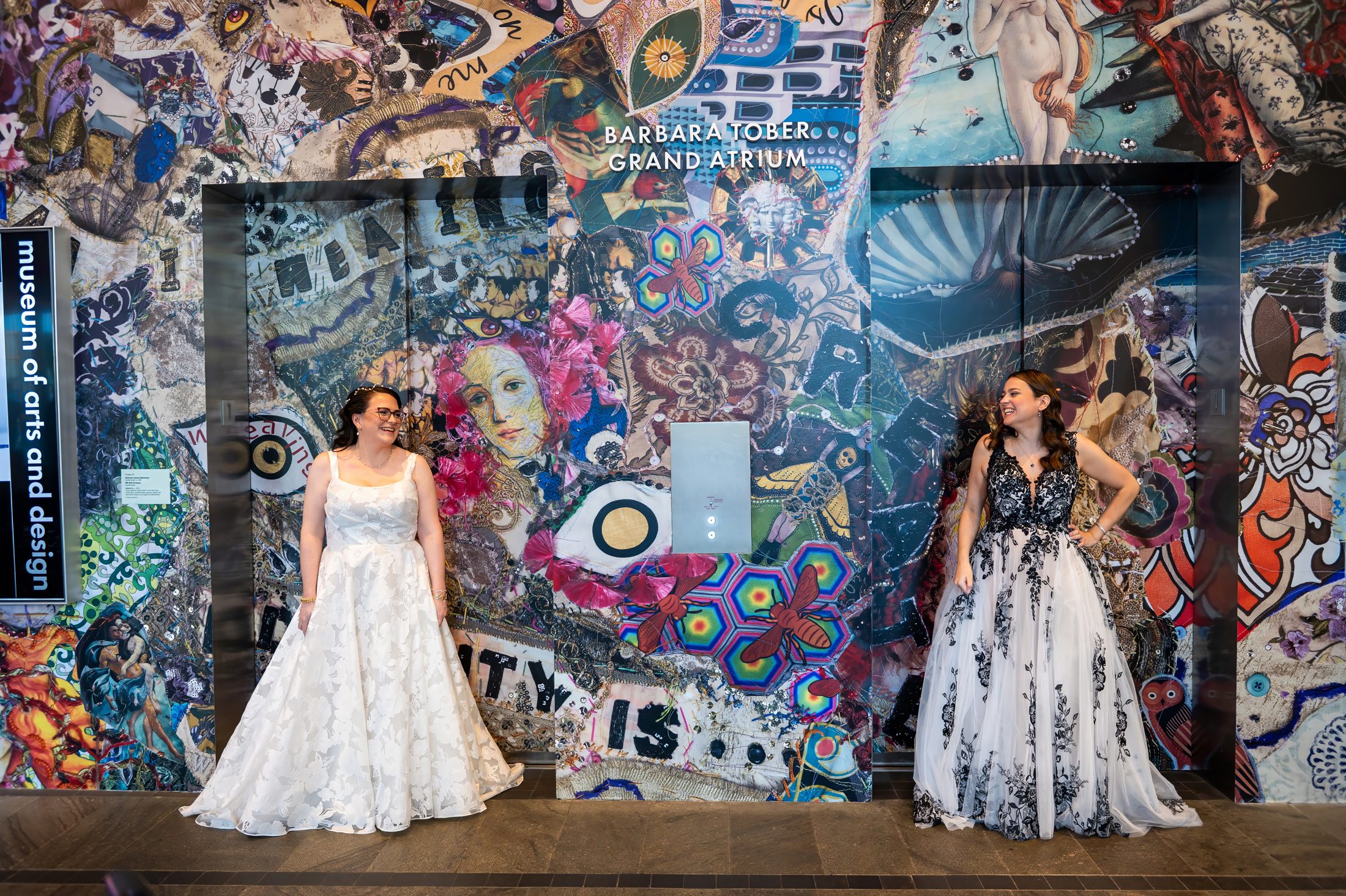 Two Brides posting for a wedding photo in front of a colorful wall at Museum of Art of Design

