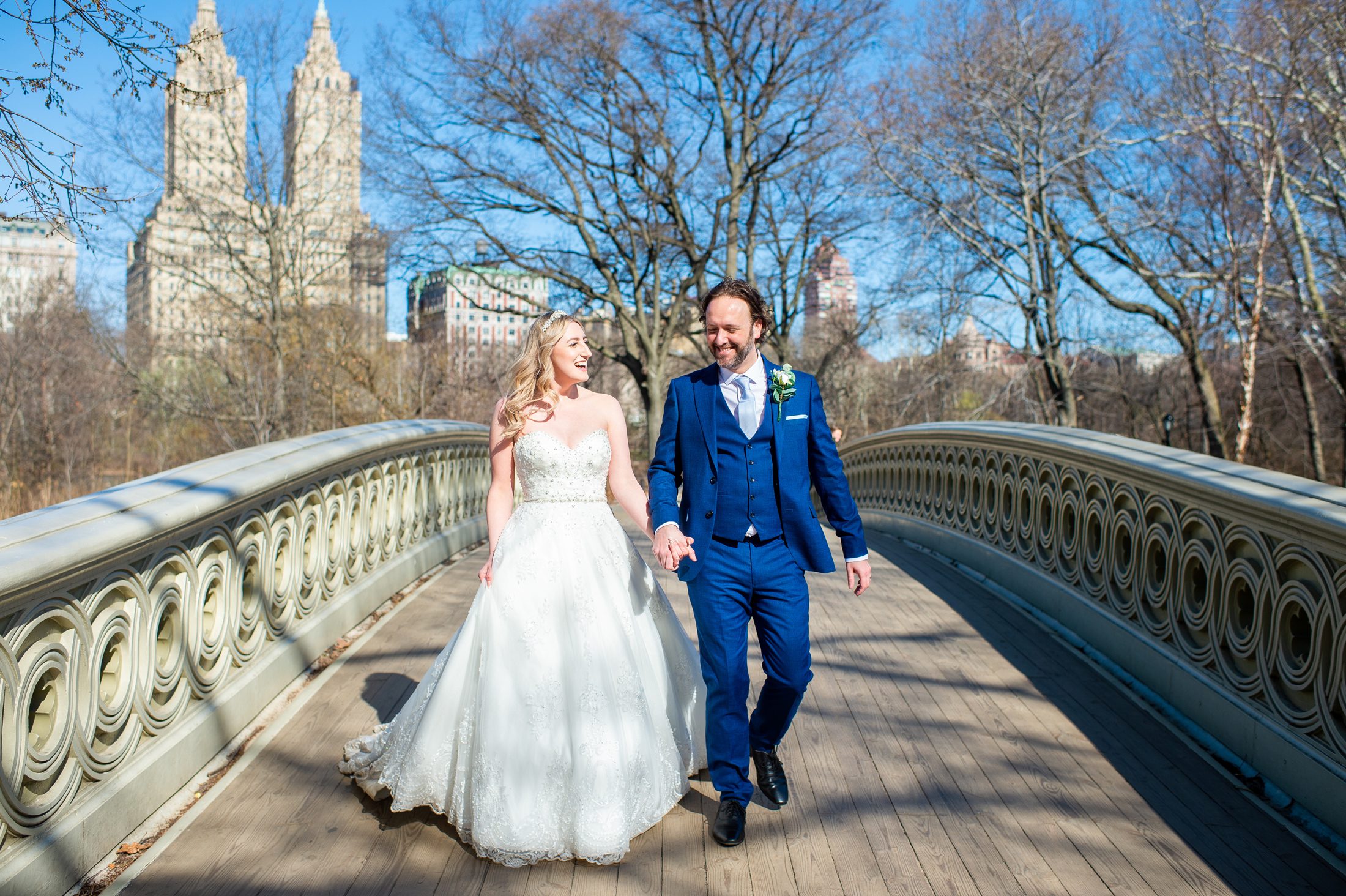 Couple walking over bow bridge after getting married in Central Park