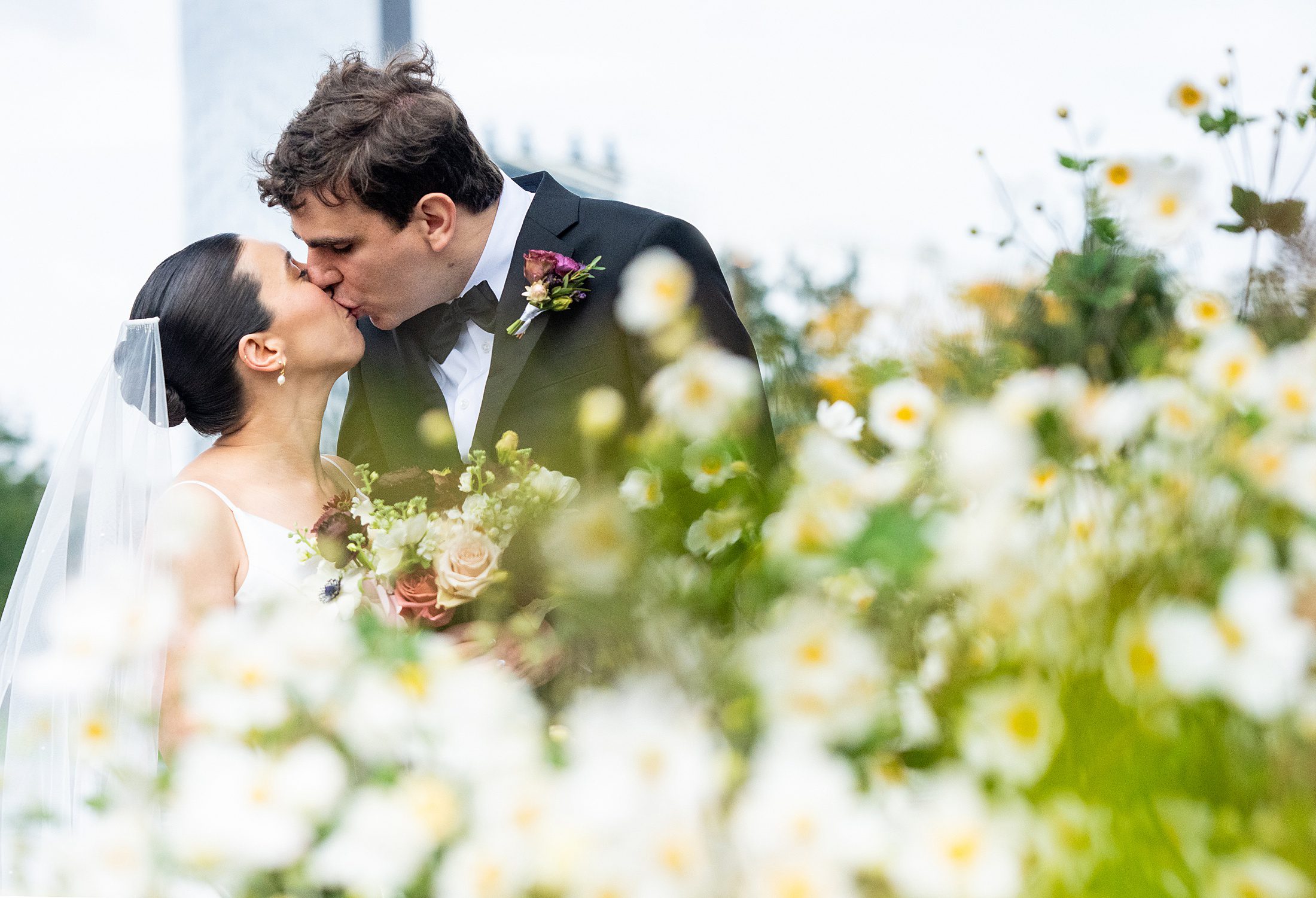 Bride and Groom kissing with flowers in Brooklyn Bridge Park 