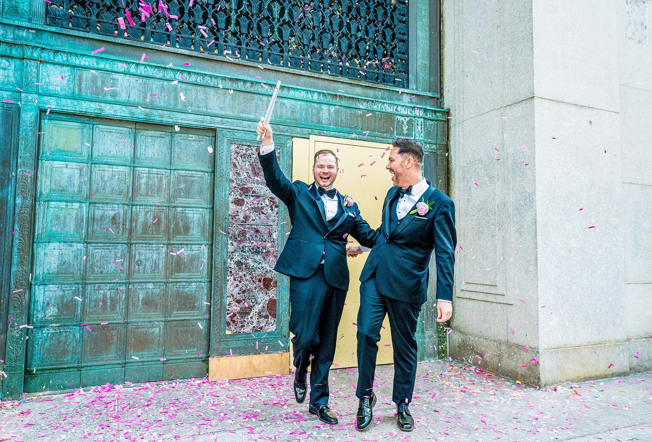 Two grooms after getting married at City Hall in NYC throwing confetti 